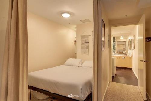 a bedroom with a white bed and a hallway at Lovely 1 Bedroom Condo in the Heart of Seattle! in Seattle