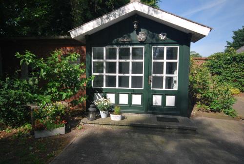 a smallshed with a green door and some plants at Ferienhäuschen Alte Schmiede, 35647 in Uplengen