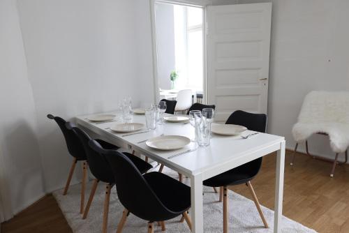 Biały stół z czarnymi krzesłami i biała jadalnia w obiekcie 2ndhomes Cozy and Quiet 2BR Apartment by the Esplanade Park w Helsinkach