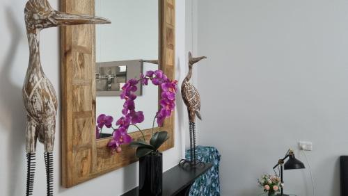 a mirror on a wall with purple flowers in a vase at The Atrium - A Stylish Home with up to 6 Bedrooms in Port Pirie