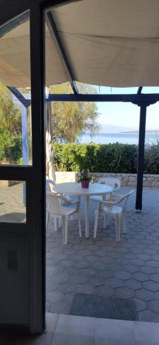 un patio con mesa, sillas y el océano en Vikos Beach Apartments, en Paralía Iríon