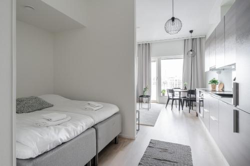 Il comprend une chambre blanche avec un lit et une cuisine. dans l'établissement 2ndhomes Tampere "Kaplan #3" Brand New Apartment - Modern & Cozy, à Tampere