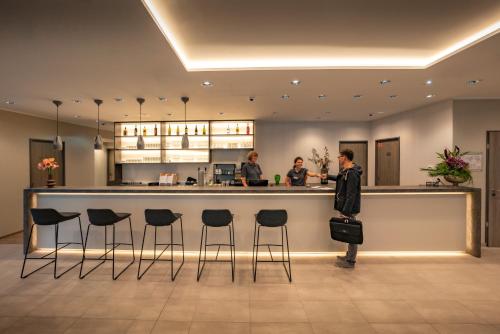 a woman standing at a bar in a restaurant at LOGINN Hotel Stuttgart Zuffenhausen in Stuttgart