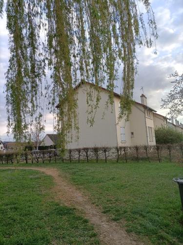 un grand bâtiment blanc dans un champ avec un arbre dans l'établissement Au Saule Pleureur, à Villers-Saint-Paul