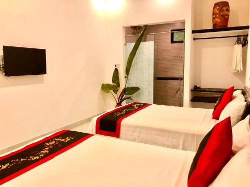 a hotel room with two beds and a television at Sunny Garden Homestay in Hoi An