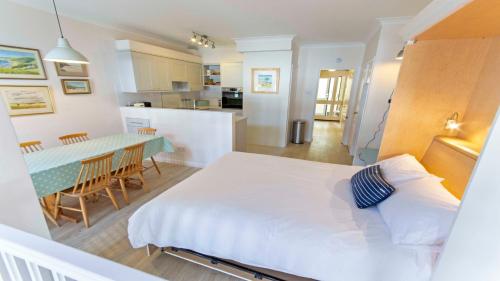 a large white bed in a room with a kitchen at Clifton Court Apt 16 with Indoor Heated Pool & Sea Views in Croyde