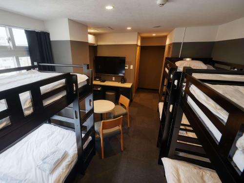 a room with bunk beds and a desk with a television at CABIN&HOTEL CONSTANT NAHA in Naha
