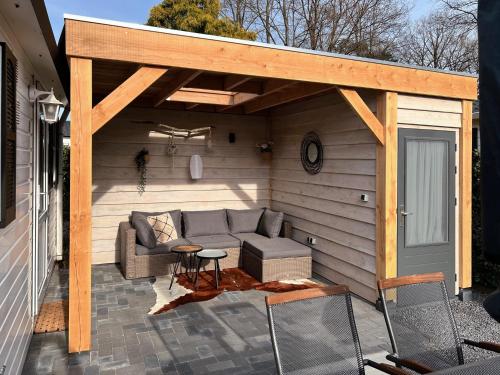 a pergola with a couch on a patio at Chalet Natuurrijk in Oisterwijk