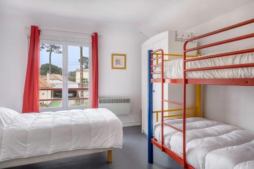 Un dormitorio con dos literas y una ventana. en Grande Brévinoise dans les pins, en Saint-Brevin-les-Pins