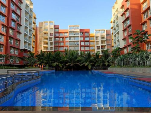 SancoaleにあるGarden View 1 BHK2BR Appt., Rio De Goa TATA Housingの一部の建物の前に青い大型スイミングプールがあります。
