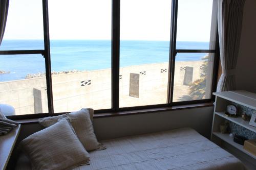 a room with large windows with a view of the beach at 香や野 kayano 海と富士山を一望できる1棟貸し宿 岡田港まで徒歩5分 in Oshima