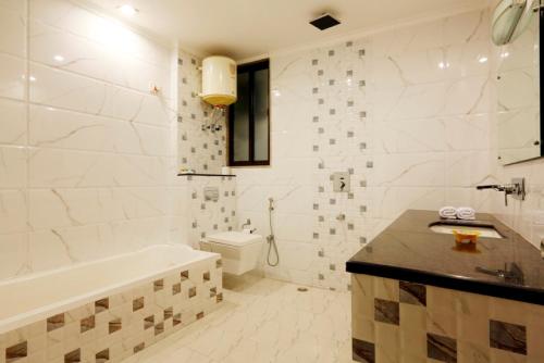 a bathroom with a tub and a toilet and a sink at Hotel Anand International in New Delhi