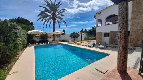uma piscina em frente a uma casa com uma palmeira em Villa Diana para 8 personas em Calpe