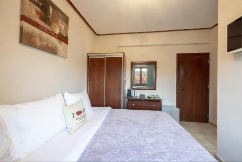 a bedroom with a large white bed and a mirror at Tsikeli Boutique Hotel Meteora - Adults Friendly in Kalabaka