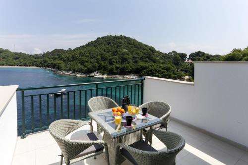 einen Tisch auf einem Balkon mit Blick auf das Wasser in der Unterkunft Apartments Posta in Saplunara