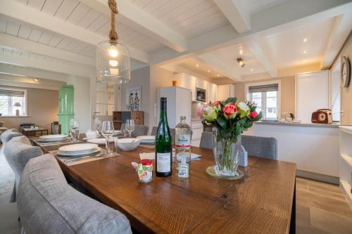 a dining room table with wine bottles and flowers on it at Lütte Hüs in Oevenum