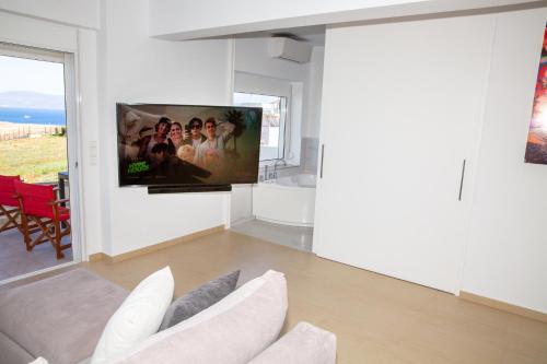 a living room with a couch and a tv on a wall at Komfort City Apartment "Elias" mit Meerblick in Lavrio in Lávrion