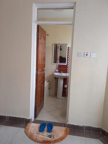 un baño con lavabo y zapatos azules sobre una alfombra en Ree homestay and safaris -JKIA en Nairobi