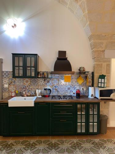 una cocina con armarios verdes y fregadero en Dimora Flò, en Brindisi