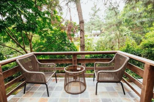 three chairs and a table on a deck with trees at AMAYA HOME - Lodge, Spa & Restaurant in Hanoi