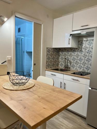 uma cozinha com armários brancos e uma mesa de madeira em Chaleureux Studio - Calme et Lumineux - Point Zéro - Proximité Plage et Centre Ville em La Grande-Motte