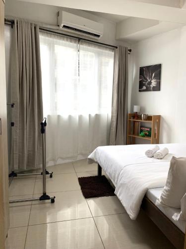 a bedroom with a white bed and a window at Cozy Crib - Shell Residences Condominium in Manila