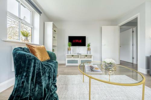 sala de estar con sofá verde y mesa de cristal en Super Luxe Central Maidenhead Apartment, en Maidenhead