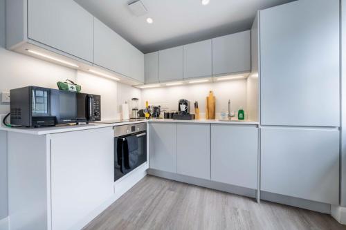 a white kitchen with white cabinets and appliances at Super Luxe Central Maidenhead Apartment in Maidenhead