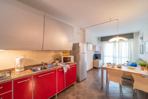 uma cozinha com armários vermelhos e uma mesa com cadeiras em Residenza Al Parco em Bibione