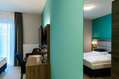 a hotel room with a bedroom with a bed and a desk at Nutzwedel Resort Farmers Lodge in Horst