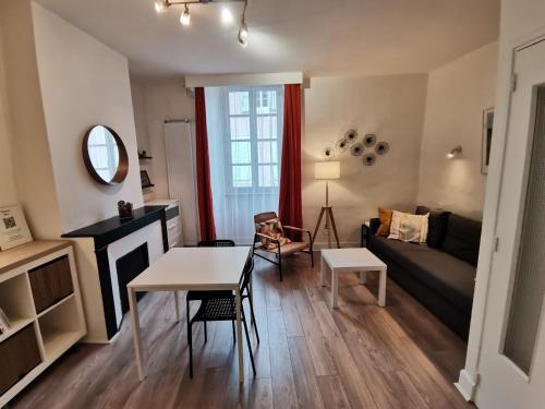 a living room with a table and a couch at Anémone - studio tout confort en centre ville in Millau