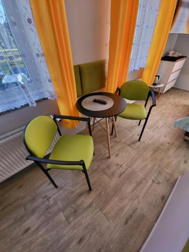 a table and chairs in a room with orange curtains at Willa Diament in Kudowa-Zdrój