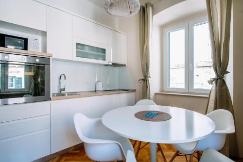 a white kitchen with a white table and chairs at AMOROZO APARTMENTS by DuHomes in Dubrovnik