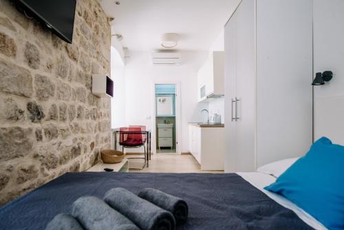 a bedroom with a stone wall and a bed with towels at AMOROZO APARTMENTS by DuHomes in Dubrovnik