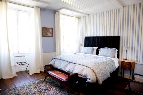 a bedroom with a bed and a chair and windows at Maison Bellachonne in Bellac