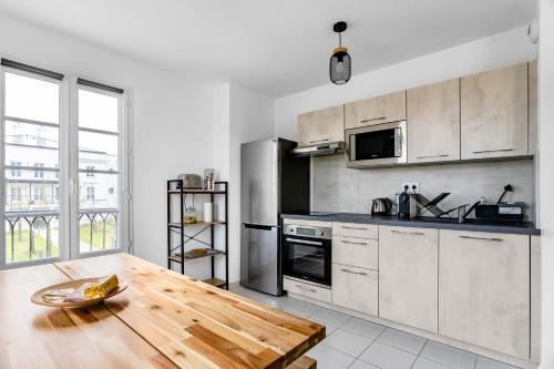 eine Küche mit einem Holztisch und einer Arbeitsplatte in der Unterkunft Disneyland-Paris 8pers,Parking, borne recharge VE, Wifi in Serris