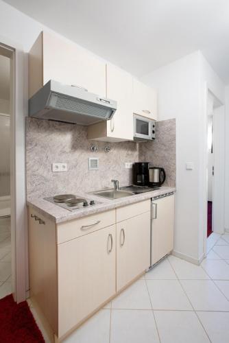 a white kitchen with a sink and a microwave at City Hotel Isar-Residenz in Landshut