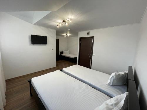 a bedroom with two beds and a tv on the wall at Dr House in Mioveni