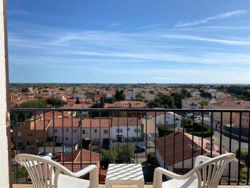a balcony with two chairs and a view of a city at Hôtel Le Belvedere in Saint-Cyprien