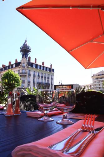 a table with two wine glasses and a red umbrella at ibis Styles Le Puy en Velay in Le Puy en Velay