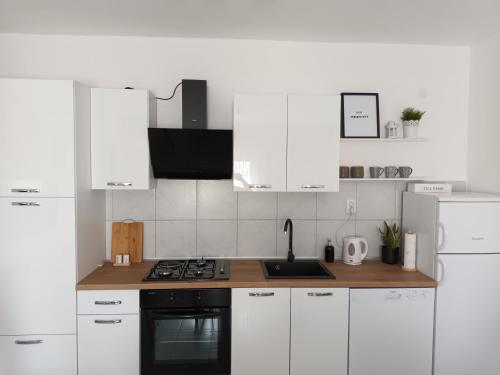 La cuisine est équipée de placards blancs et d'un four avec plaques de cuisson. dans l'établissement Holiday house Ana, à Skradin