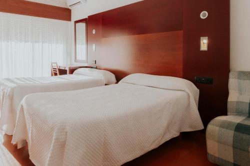 twee bedden in een hotelkamer met witte lakens bij Hotel Novo Muiño in A Guarda