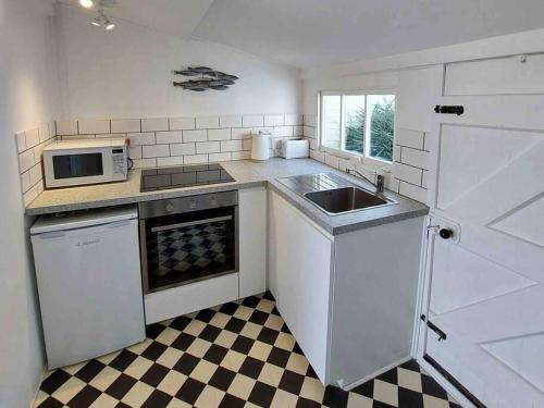 een witte keuken met een wastafel en een magnetron bij Sea Forever - Beautiful Chalet which Overlooks the Sea! Amazing Views,Lovely Interior and Set Within the Best Part of Lyme with Beaches, Restaurants and Harbour all on your Doorstep! Rated Highly in Lyme Regis