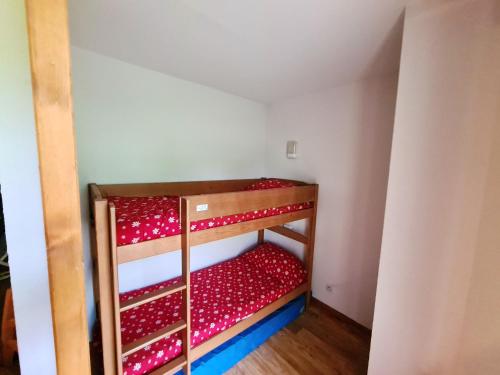 Cette chambre comprend 2 lits superposés dotés de draps rouges. dans l'établissement Appartement chaleureux à Chamrousse, 42 m², parking inclus, à Chamrousse