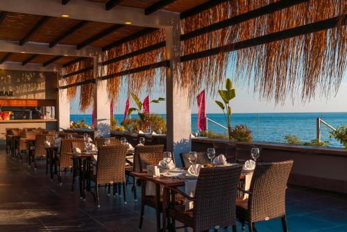 a restaurant with tables and chairs with the ocean in the background at White City Beach Adult Only in Konaklı
