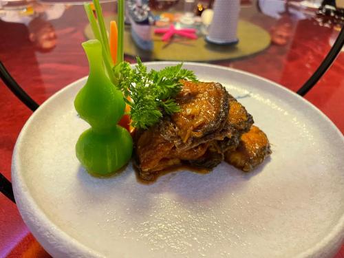 a white plate with meat and broccoli on a table at Crowne Plaza Yantai Sea View by IHG in Yantai