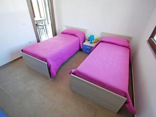 サンタンナ・アッレージにある2 bedrooms house with enclosed garden and wifi at Sant'Anna Arresi 3 km away from the beachのピンクのシーツが備わる客室内のベッド2台