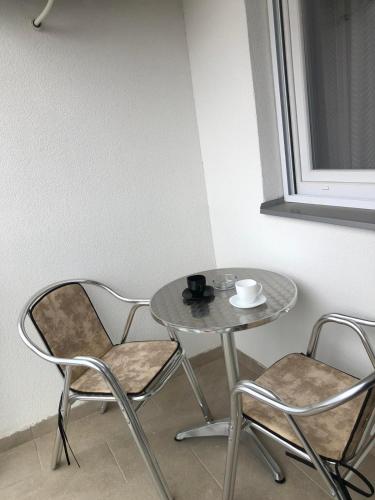 a table and two chairs and a table with a cup on it at Tri palme in Banja Koviljača