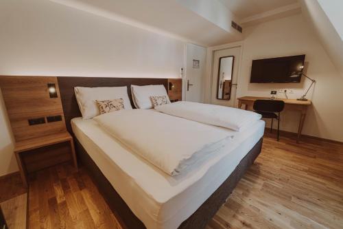 a large white bed in a room with a desk at Burghotel Schlaining in Stadtschlaining