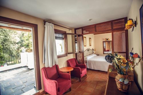 a bedroom with a bed and two chairs and a window at Finca Los Llanos in Capileira